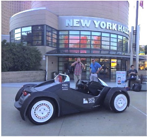 The Local Motors “Strati” 3D-Printed, open-source, crowd-designed-winner car parked in front of MakerCon New York, NYSCI—”built” in 40 hours of realtime printing on a public exhibit-stand at the Intl Manufacturing Tech Show 2014 (in Chicago Sept 8 to 13, McCormick Place). Photo compliments J. E. Earle/Eventifier.